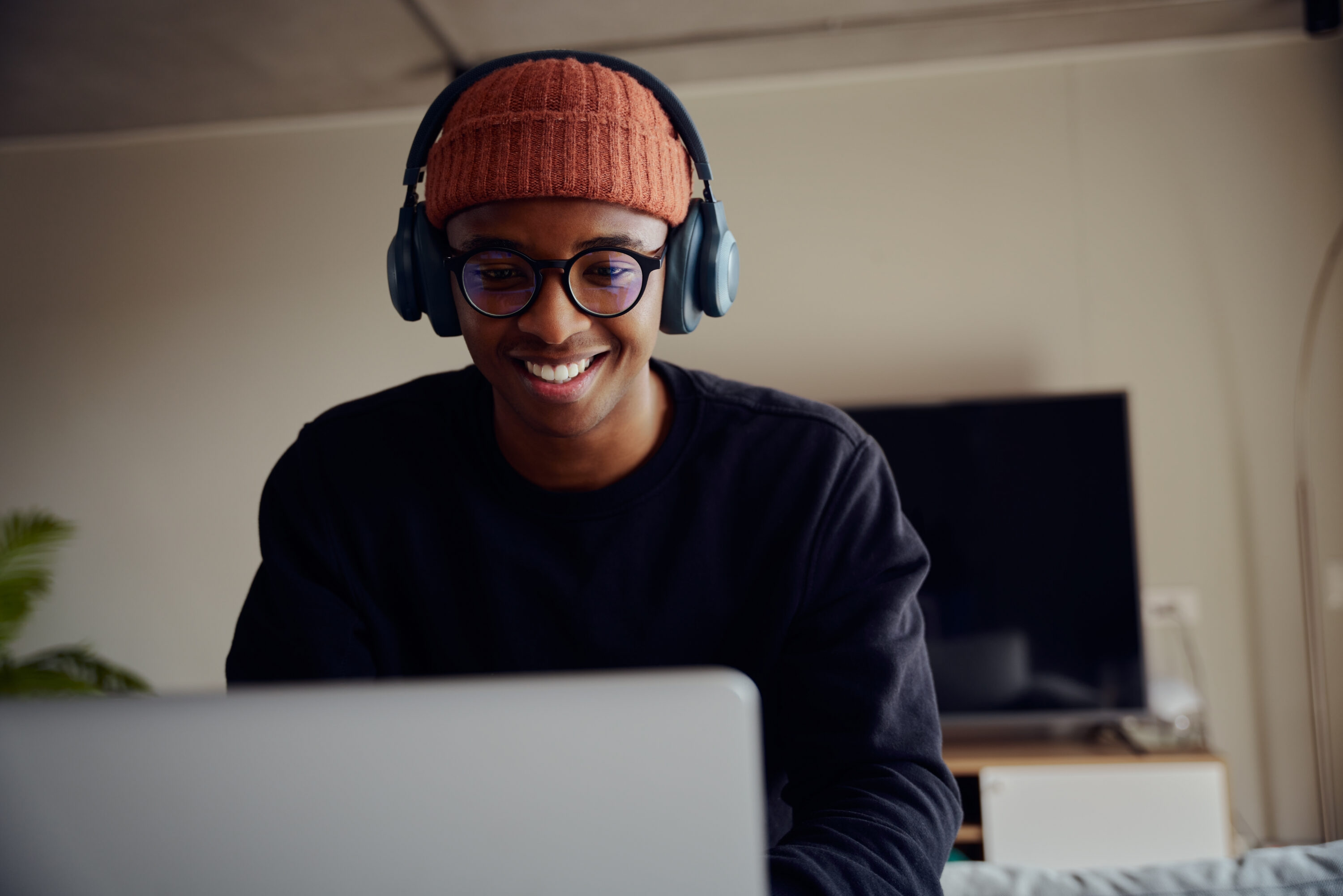 African American male working from home using laptop. Happy African American male working from home with headphones on. High quality photo African American male working from home using laptop. Happy African American man working from home with headphones on for virtual meeting. High quality photo