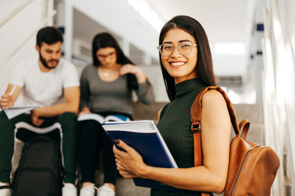 Portrait of young Brazilian student with backpack carrying books in college. Portrait of young Brazilian student with backpack carrying books in college.
