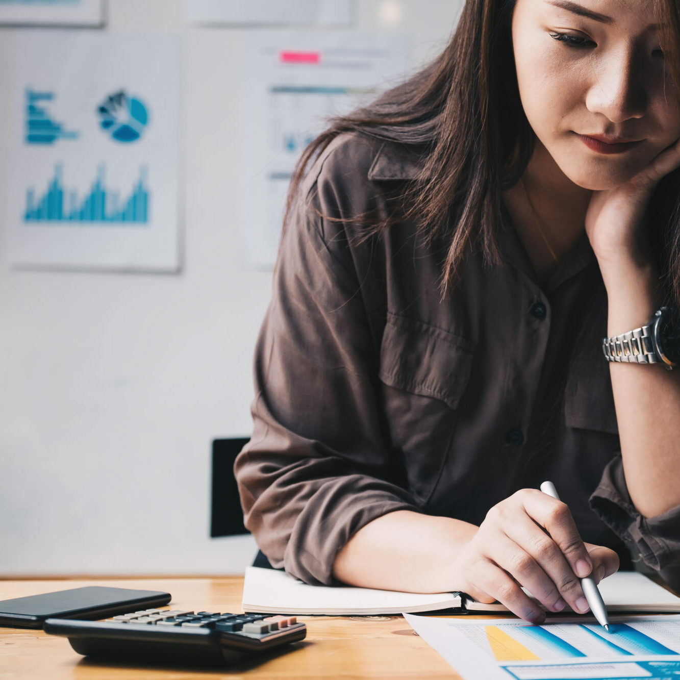 Business woman using calculator for do math finance on wooden de Business woman using calculator for do math finance on wooden desk in office and business working background, tax, accounting, statistics and analytic research concept